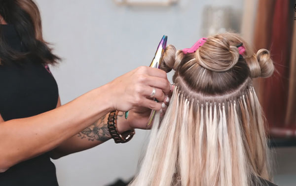Professional stylist applying high quality hair extensions in a salon